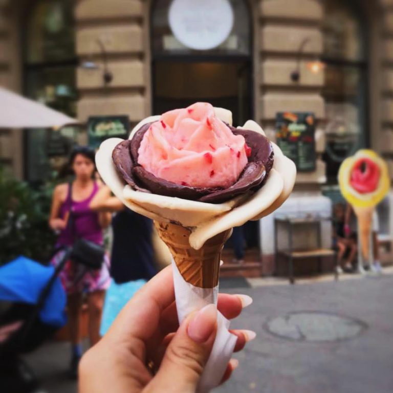 woman's hand holding ice cream on a waffle cone on the street