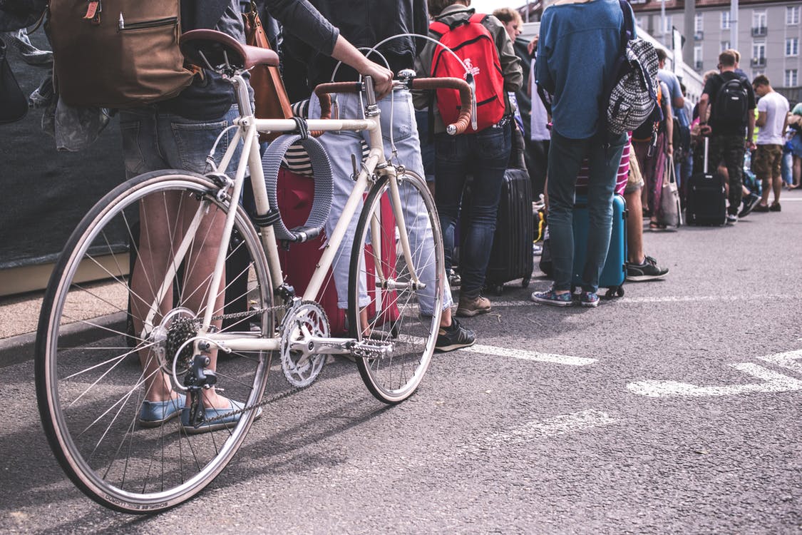 woman holding a road bike while queuing in the crowd