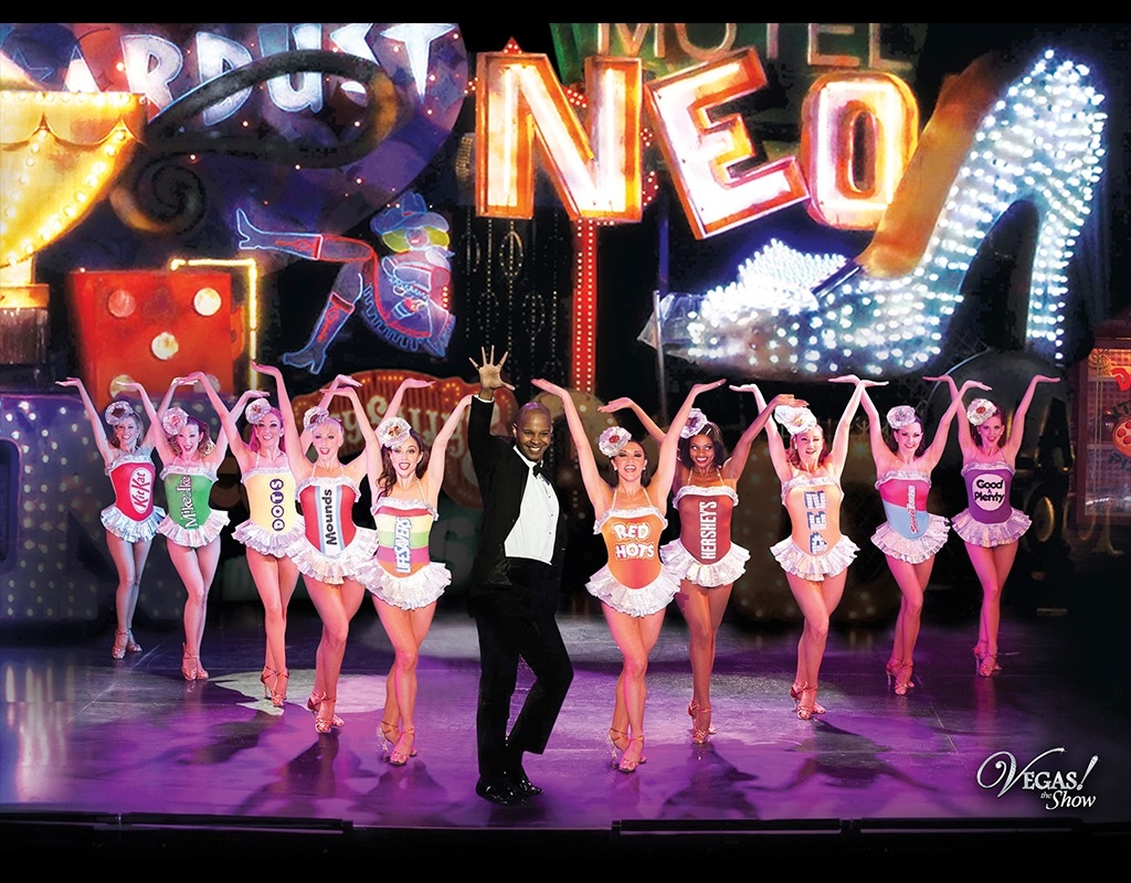 group of female dancers and the lead male performer in the center on vegas the show event