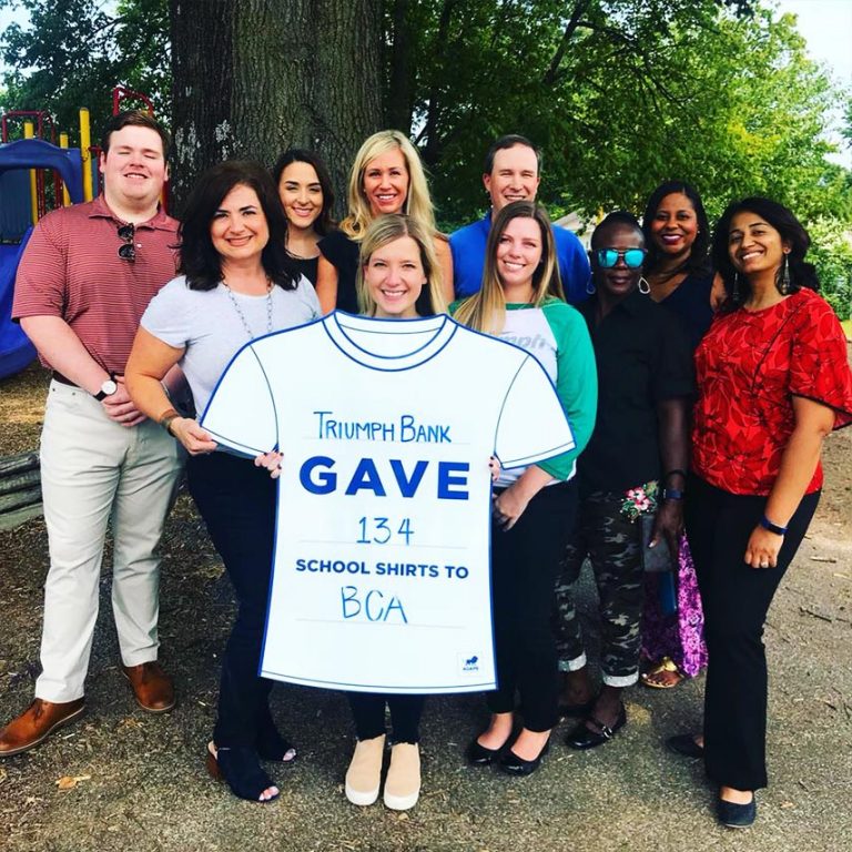 group of people photo and a woman in the middle holding a white shirt with text on it