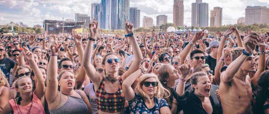 crowded people wearing wristbands raising hands