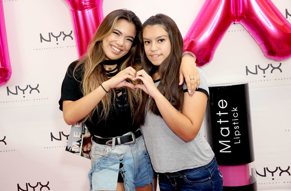 two ladies doing heart sign in their fingers