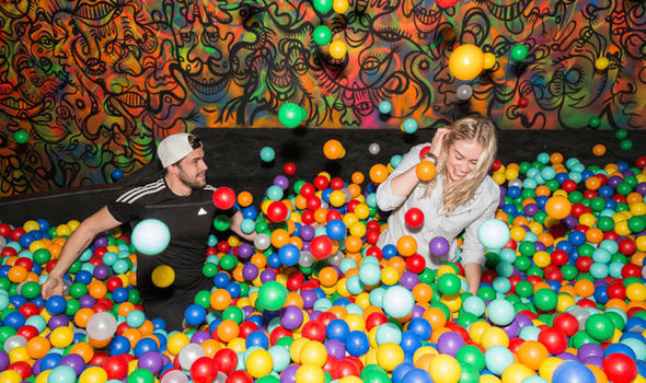 men and women playing in a ball pit