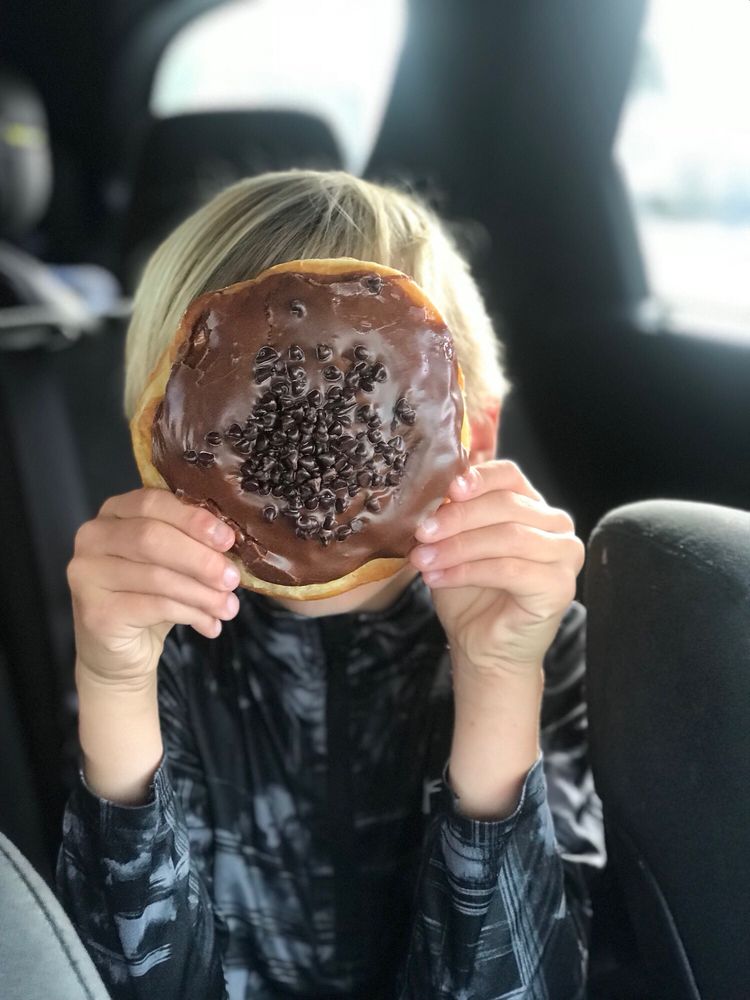 the boy covered his face with a piece of chocolate donut