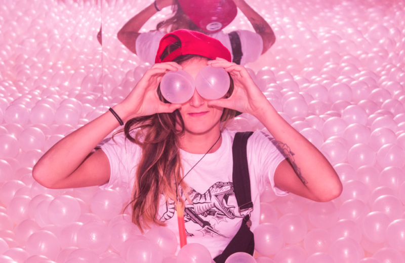 girl wearing a red cap and holding two pink balls placed in her eyes