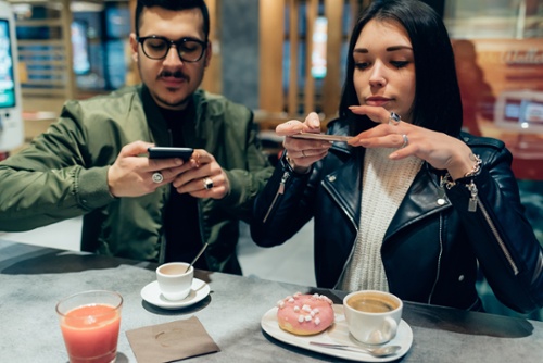 men and women wearing leather jackets photographing their food using their mobile phones