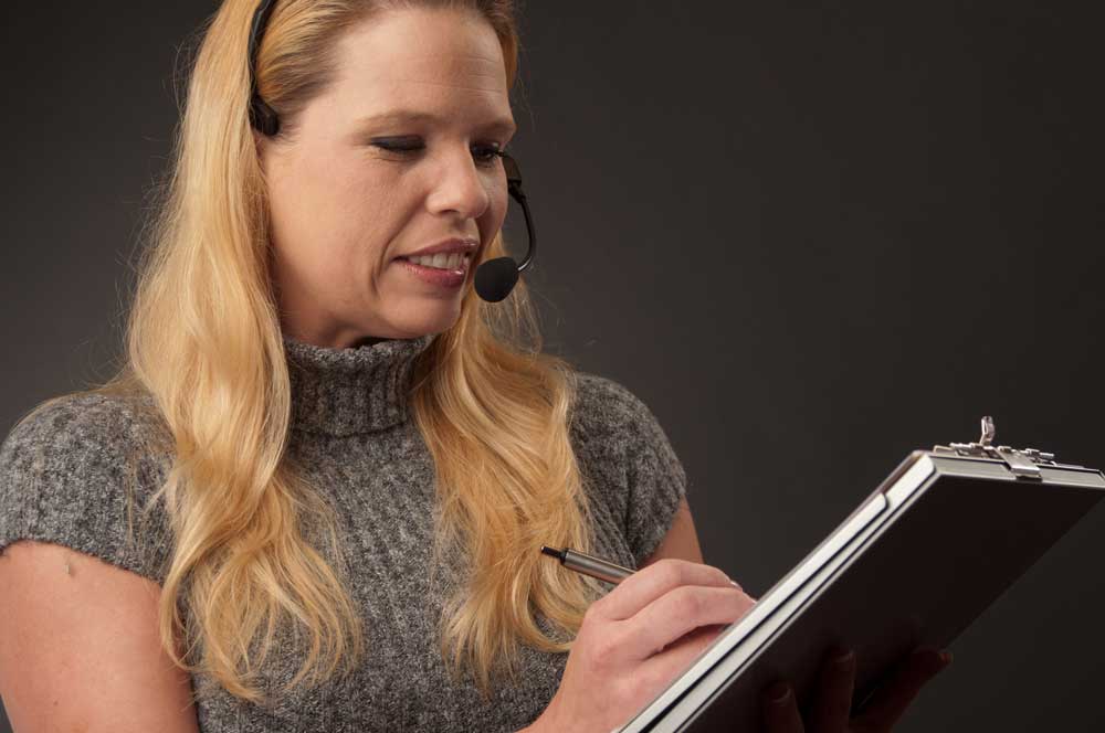 a woman wearing headset and writing notes