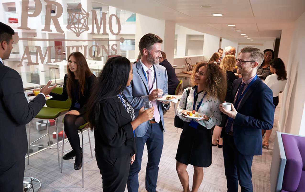 a crowd all wearing business attire talking to each other while holding a plate of food