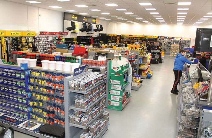a man wearing a blue jacket pays his purchased item at the cashier in an electrical hardware store