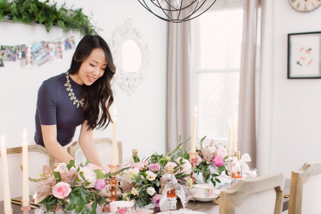 a smiling woman is arranging flowers on the table