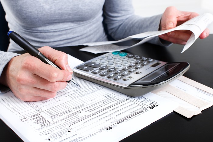 a person with calculator filling out a tax form for payment