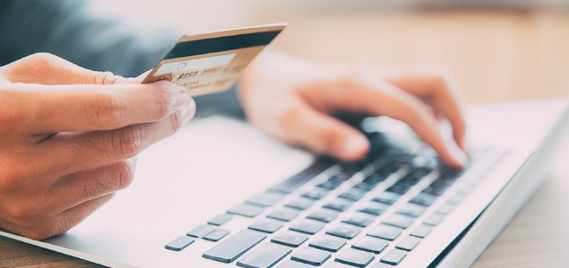 a man is typing on his laptop with credit card to buy online