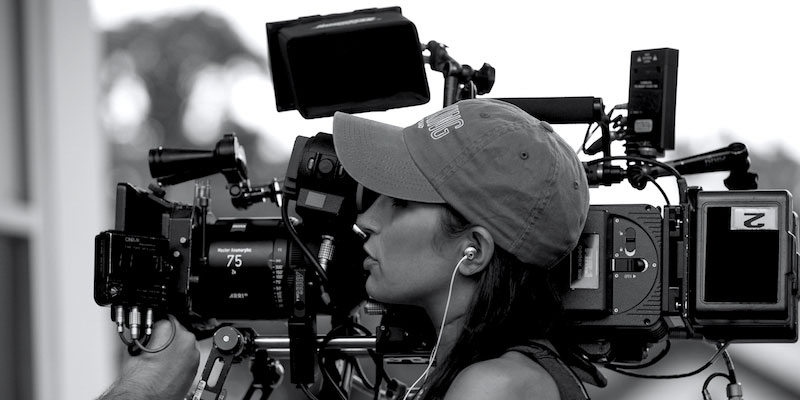 a female film maker looking at video camera