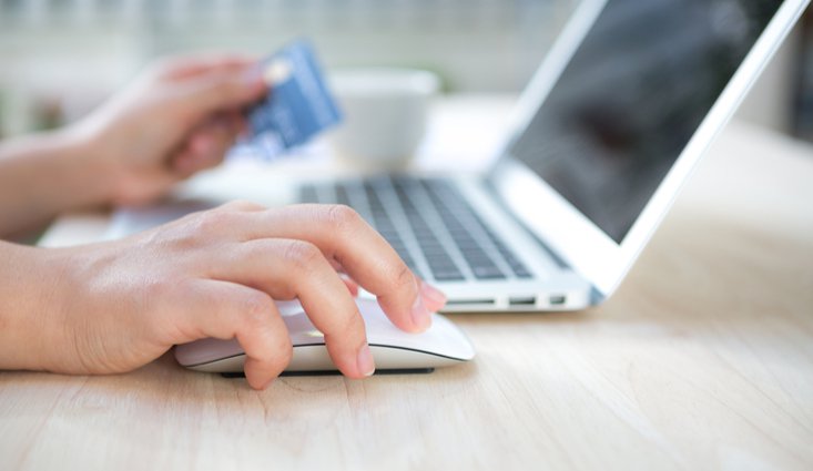 right hand holding a mouse and left hand holding a card and laptop at the middle