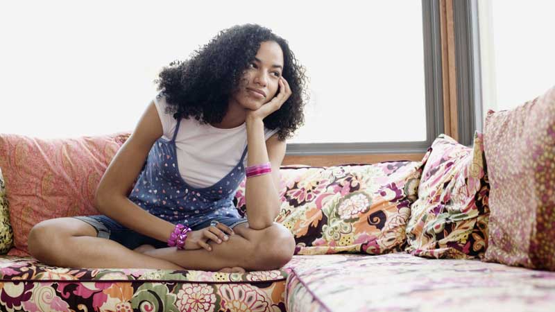 bored curly haired woman sitting on sofa