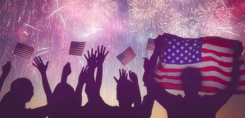 people raise their hands holding the USA flag celebrating the fourth of July event