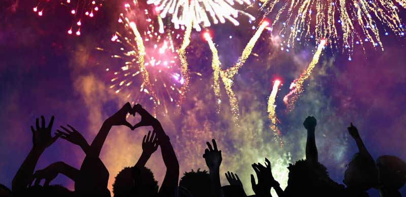 people raised their hands watching the fireworks display on new year's eve