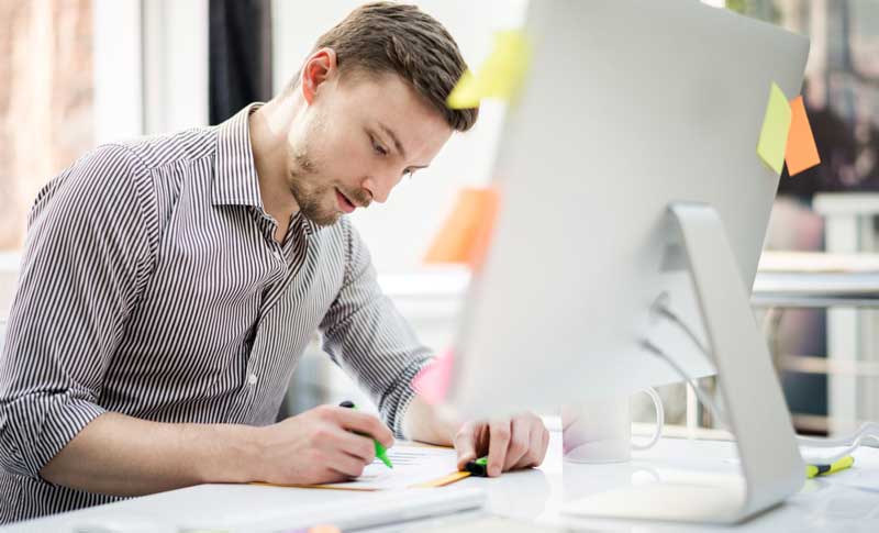 a man writing on paper using color pen