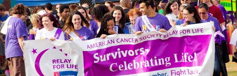 people walk holding banner by american cancer society for relay for life event