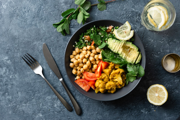 a vegan meal with knife and fork, lemon, salt and mint leaves around