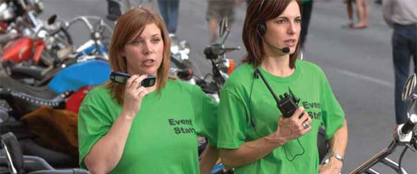two women in green shirts holding walkie talkies