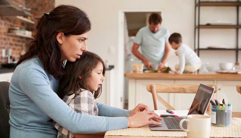 a photo mom working at home in front of her laptop with her family