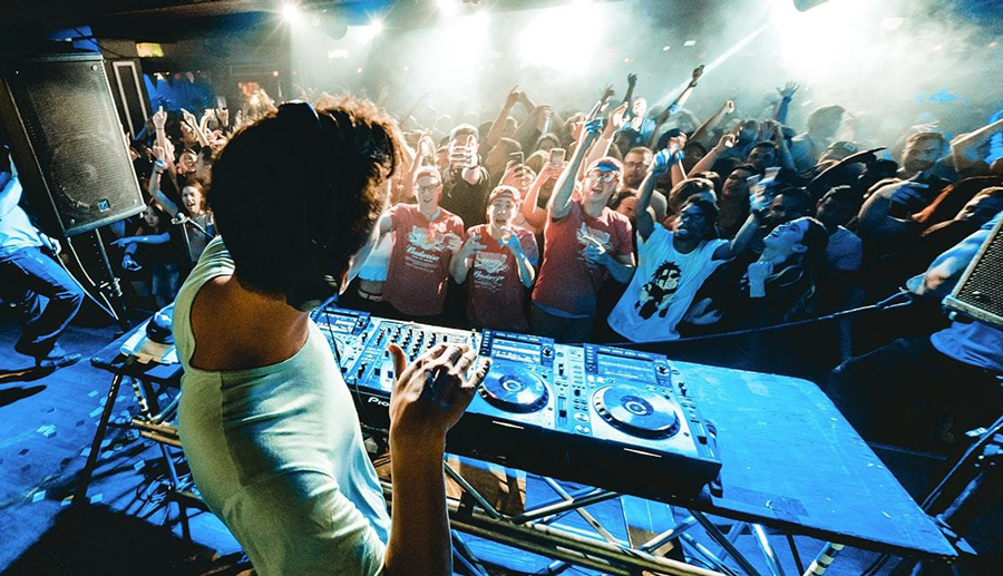 a DJ plays and mixes music for most cheerful people with raised hands