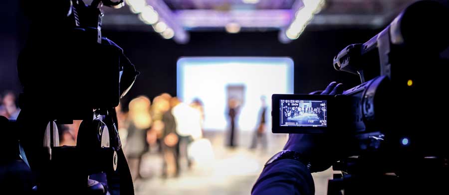 a camera pointing at people talking and a backdrop