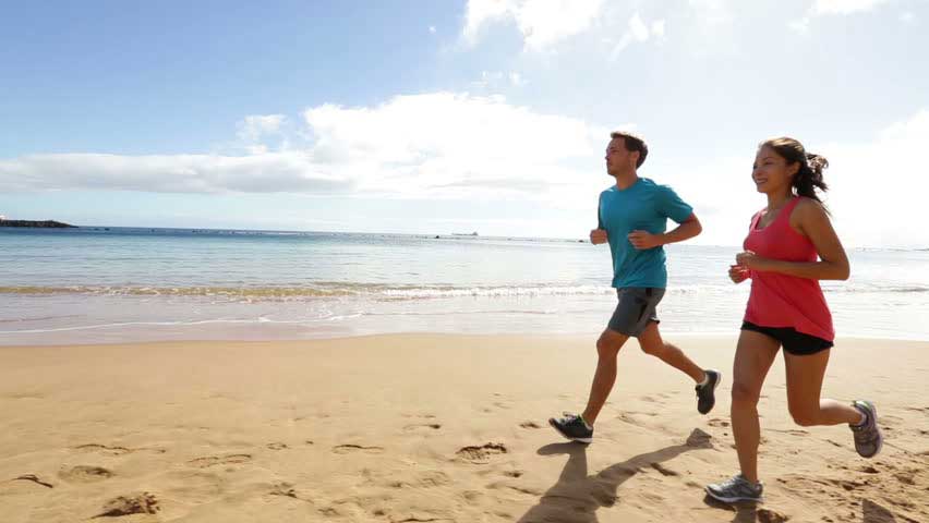 a man and woman running on the beach