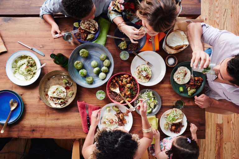 A family eating a variety of foods on a picnic table