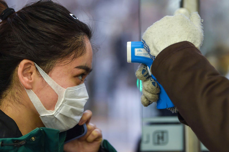 A woman in a mask getting her temperature taken