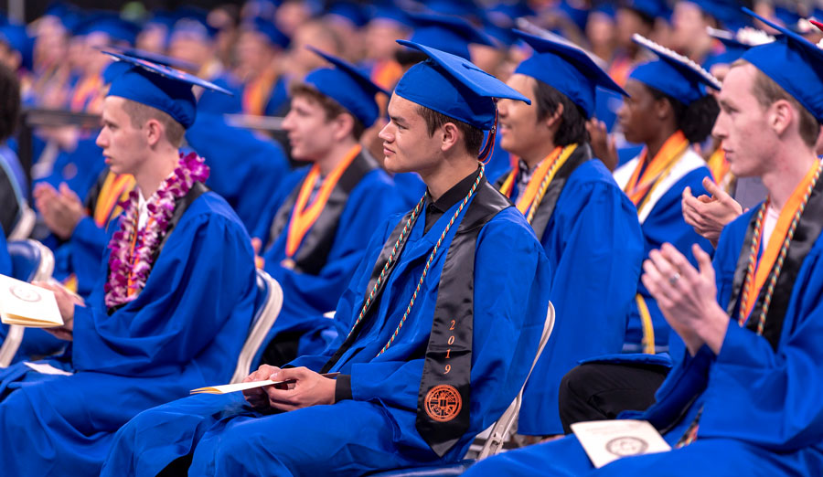 students in their blue graduation gown and cap clapping