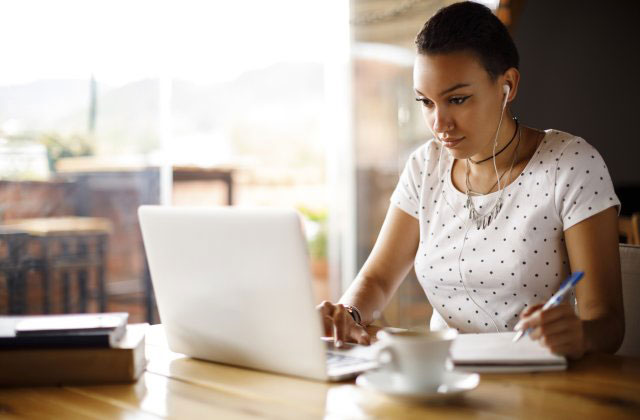 A girl looking at her computer and listening to music