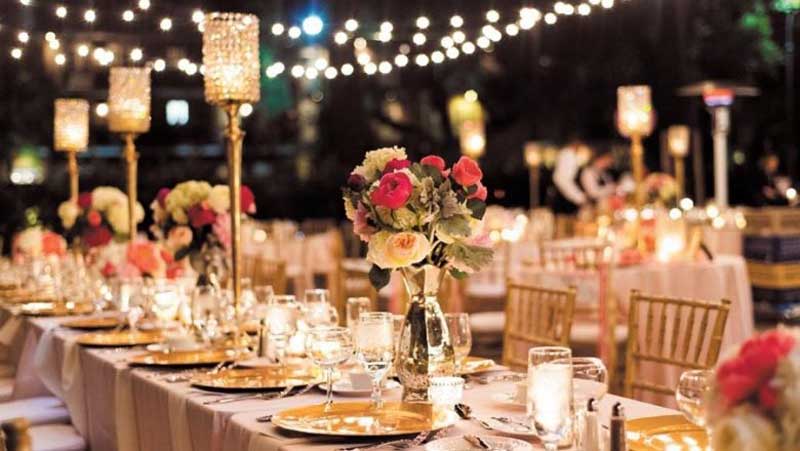 a long table with center pieces, plates, glasses at a dinner party