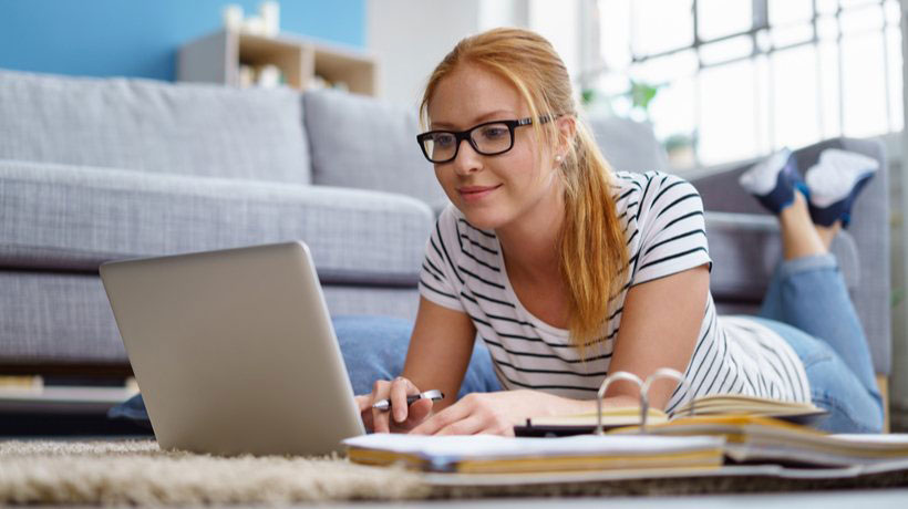 a girl with glasses on looking at her computer and smiling