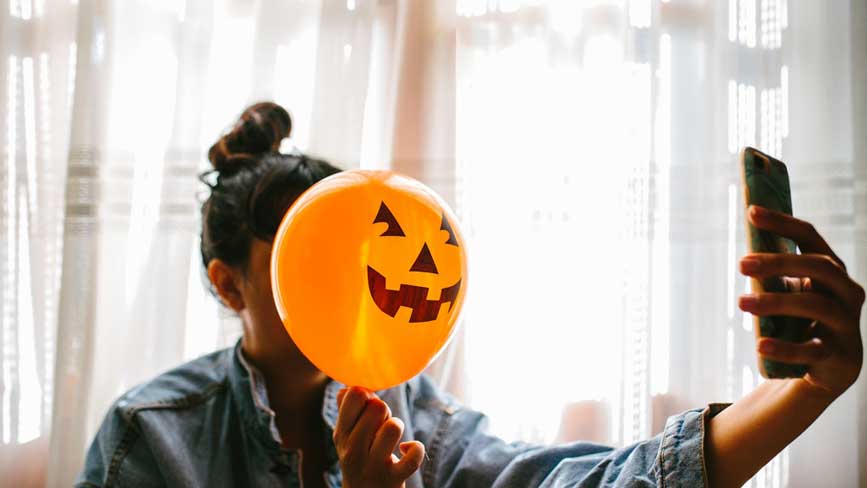 a-girl-holding-a-pumpkin-balloon-taking-a-selfie