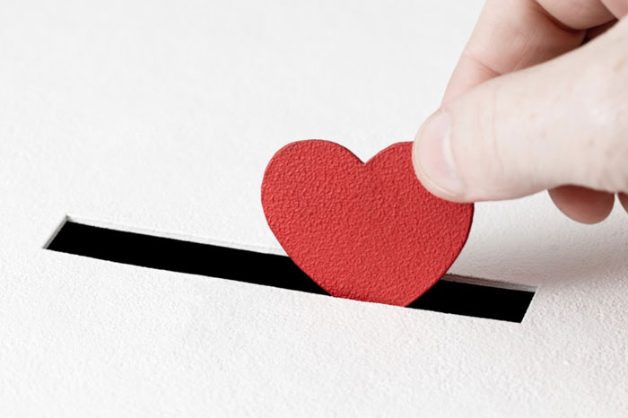 a person putting a paper heart into a box