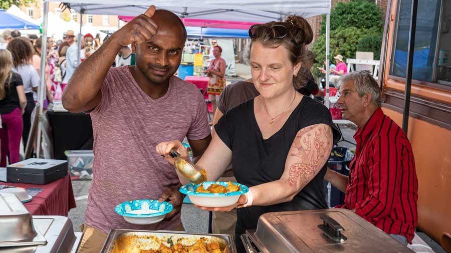 a-person-serving-a-man-food-at-a-festival